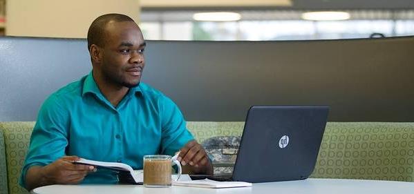 Guy in a library on a laptop.