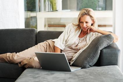 Woman sitting on couch with laptop.